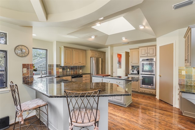 kitchen with a breakfast bar, kitchen peninsula, appliances with stainless steel finishes, and decorative backsplash