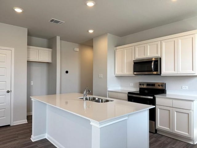 kitchen featuring visible vents, a kitchen island with sink, a sink, stainless steel appliances, and white cabinets