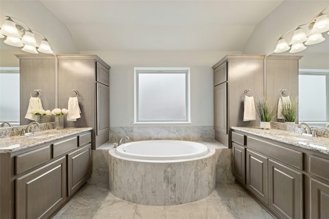 bathroom with tiled bath, vanity, and lofted ceiling