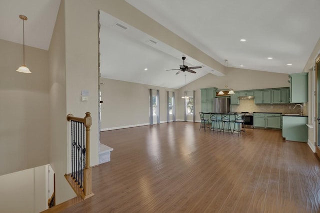 unfurnished living room with ceiling fan, wood-type flooring, sink, and lofted ceiling with beams