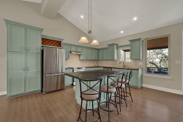 kitchen with appliances with stainless steel finishes, pendant lighting, sink, backsplash, and light hardwood / wood-style floors