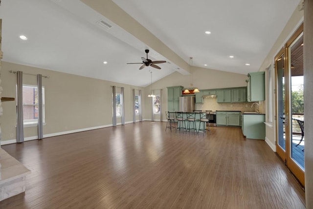 unfurnished living room with sink, lofted ceiling with beams, dark hardwood / wood-style floors, and a healthy amount of sunlight