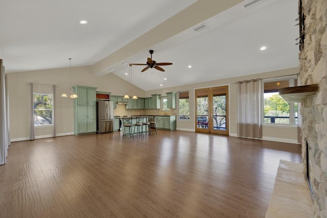 unfurnished living room featuring dark wood-type flooring, a fireplace, ceiling fan with notable chandelier, and lofted ceiling with beams