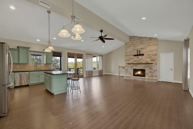 kitchen with a kitchen island, appliances with stainless steel finishes, dark hardwood / wood-style flooring, and decorative light fixtures