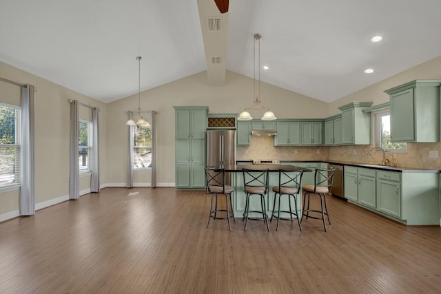 kitchen with stainless steel appliances, sink, decorative backsplash, and decorative light fixtures