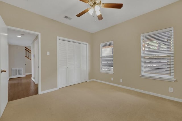 unfurnished bedroom with multiple windows, carpet flooring, ceiling fan, and a closet