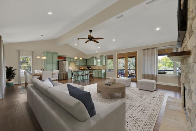 living room featuring lofted ceiling with beams, light wood-type flooring, ceiling fan with notable chandelier, and a fireplace