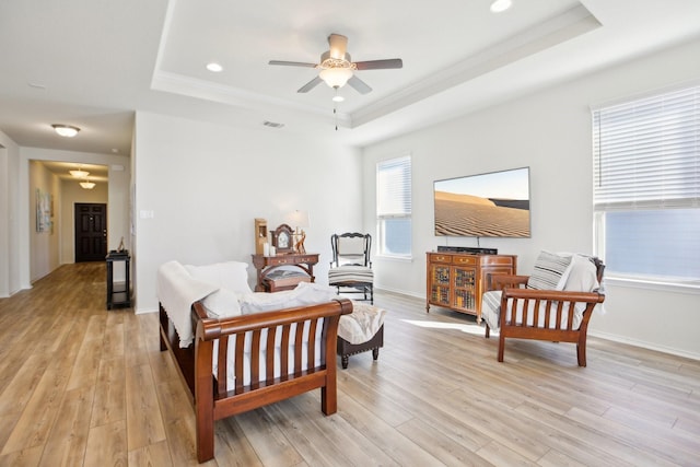 living room featuring a healthy amount of sunlight, a tray ceiling, and light hardwood / wood-style floors