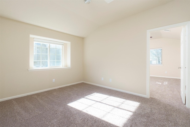 empty room featuring vaulted ceiling, a wealth of natural light, and carpet flooring