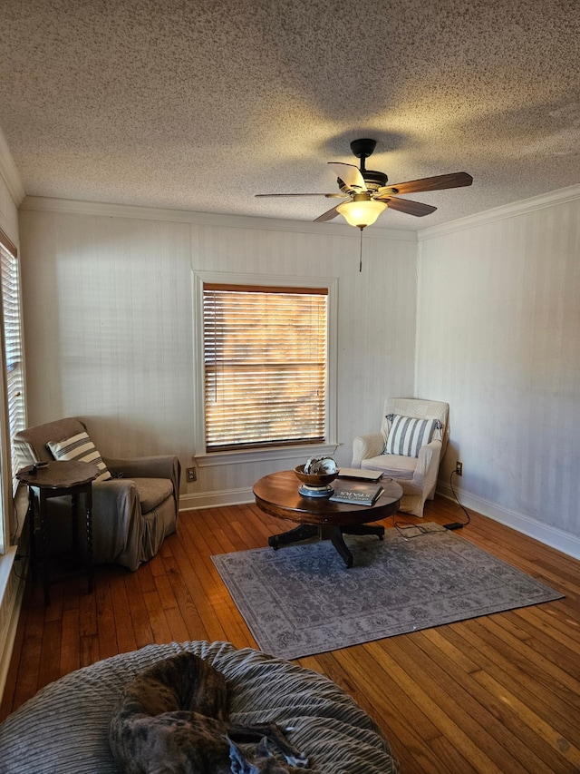 sitting room featuring ceiling fan, hardwood / wood-style floors, ornamental molding, and a textured ceiling