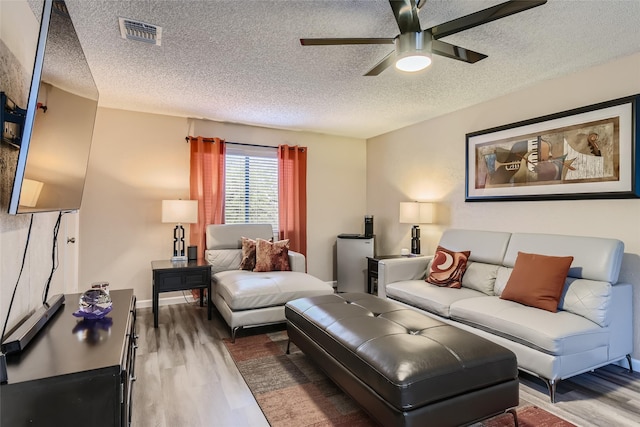 living room with ceiling fan, wood-type flooring, and a textured ceiling