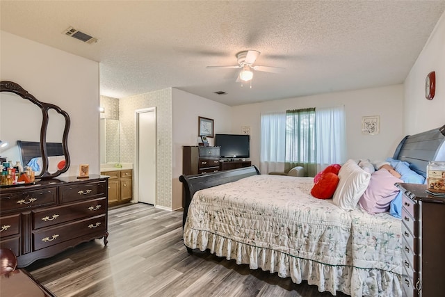 bedroom featuring a textured ceiling, ceiling fan, connected bathroom, and light hardwood / wood-style flooring