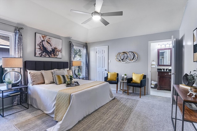 bedroom with ceiling fan, light colored carpet, lofted ceiling, and ensuite bath