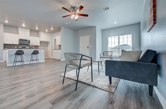 living room with ceiling fan and light hardwood / wood-style floors