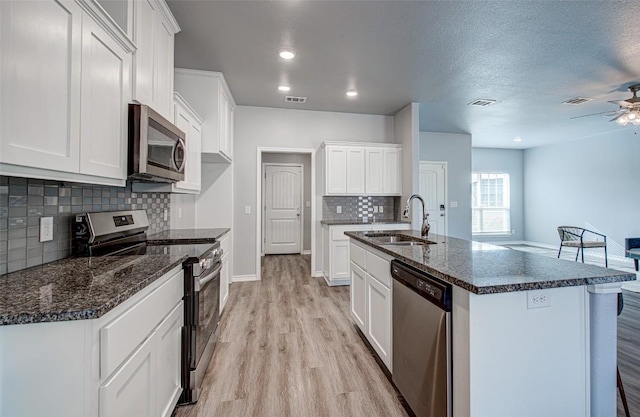 108 Elmer Ave, Burnet, TX 78611 - kitchen featuring appliances with stainless steel finishes, light wood-style floors, ceiling fan, decorative backsplash, and white cabinetry
