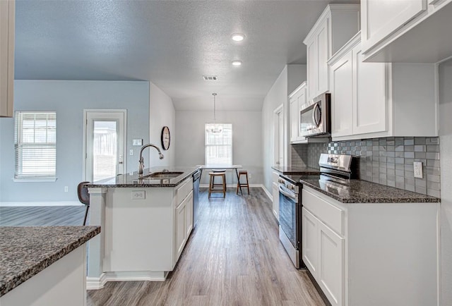 108 Elmer Ave, Burnet, TX 78611 - kitchen featuring stainless steel appliances, light wood-style floors, white cabinets, dark stone counters, and a textured ceiling