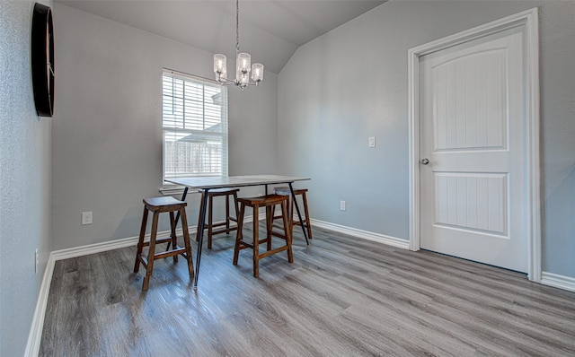 dining room featuring light hardwood / wood-style flooring, an inviting chandelier, and vaulted ceiling