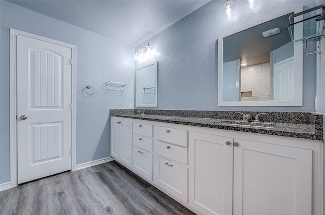108 Elmer Ave, Burnet, TX 78611 - bathroom featuring a textured wall, wood finished floors, double vanity, and a textured ceiling