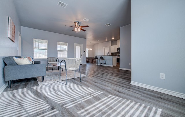 living room featuring ceiling fan with notable chandelier and hardwood / wood-style flooring