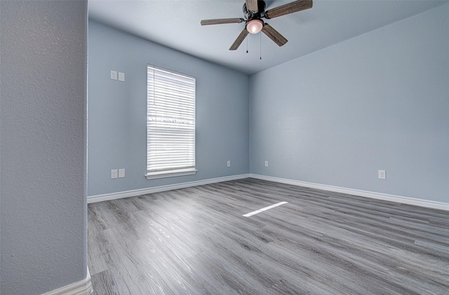 empty room with ceiling fan, a wealth of natural light, and wood-type flooring