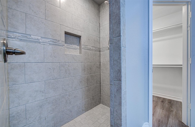 bathroom featuring wood-type flooring and a tile shower