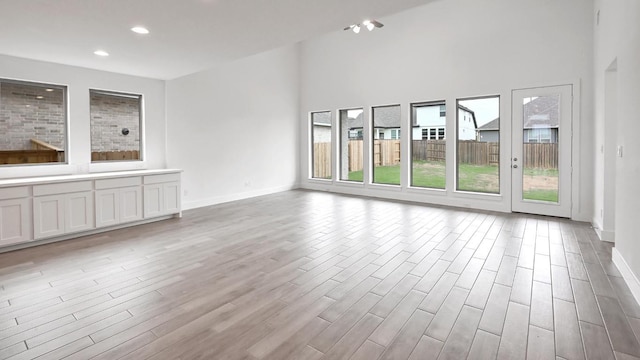 330 Allegheny Way, Kyle, TX 78640 - unfurnished living room with light wood-style floors, recessed lighting, and a towering ceiling