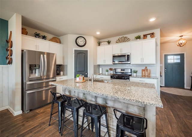 kitchen with sink, stainless steel appliances, white cabinets, and a center island with sink