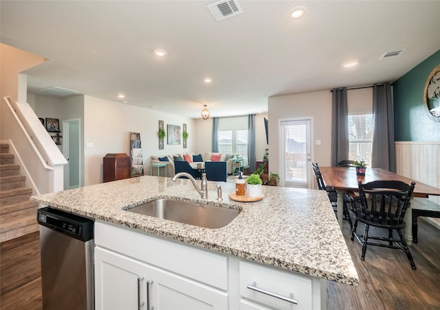 kitchen with a wealth of natural light, white cabinetry, sink, stainless steel dishwasher, and light stone counters