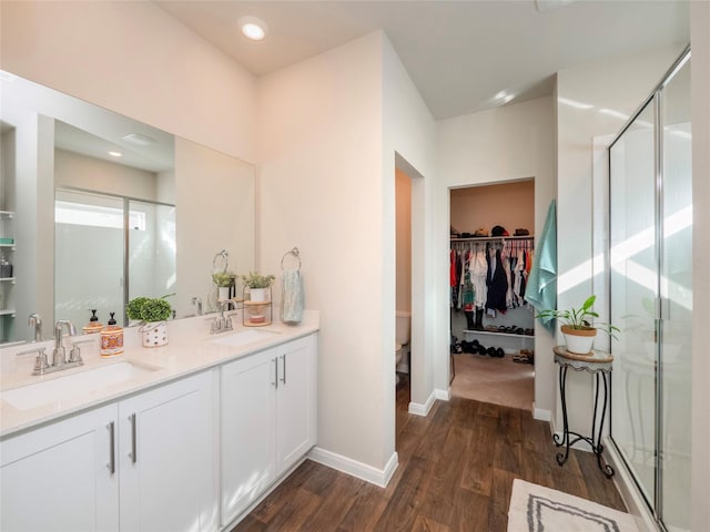 bathroom with vanity, hardwood / wood-style flooring, a shower with door, and toilet