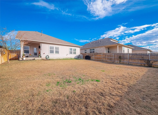 rear view of house with cooling unit, a patio area, and a lawn