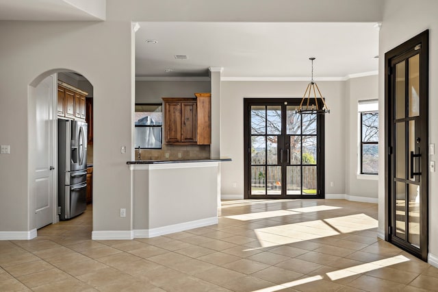 kitchen with french doors, an inviting chandelier, stainless steel fridge with ice dispenser, light tile patterned floors, and crown molding