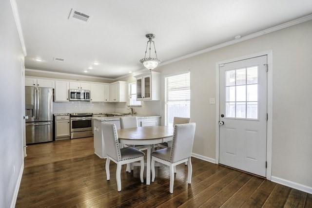 dining room featuring dark wood-type flooring, ornamental molding, and sink