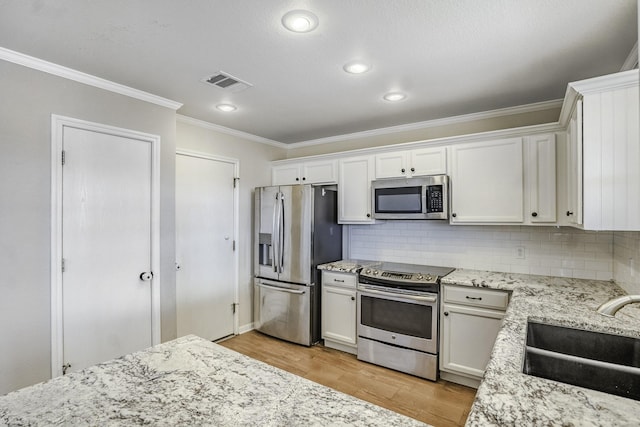 kitchen featuring tasteful backsplash, light hardwood / wood-style floors, sink, white cabinetry, and stainless steel appliances