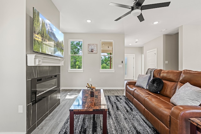 living room featuring light wood-type flooring, a tiled fireplace, recessed lighting, baseboards, and ceiling fan