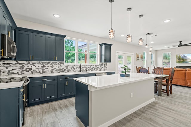 kitchen featuring stainless steel microwave, backsplash, light countertops, a wealth of natural light, and a sink