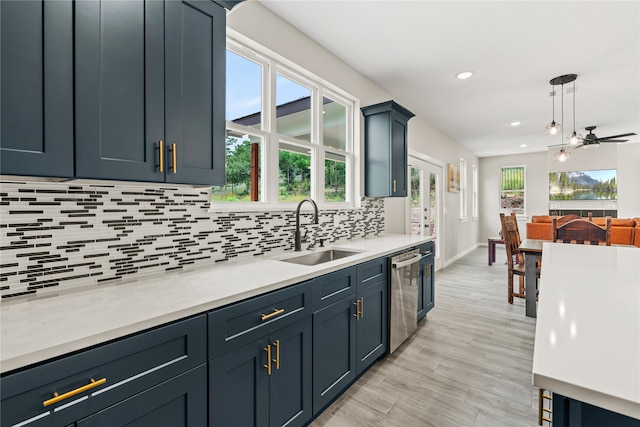 kitchen featuring a sink, a healthy amount of sunlight, light countertops, decorative backsplash, and stainless steel dishwasher