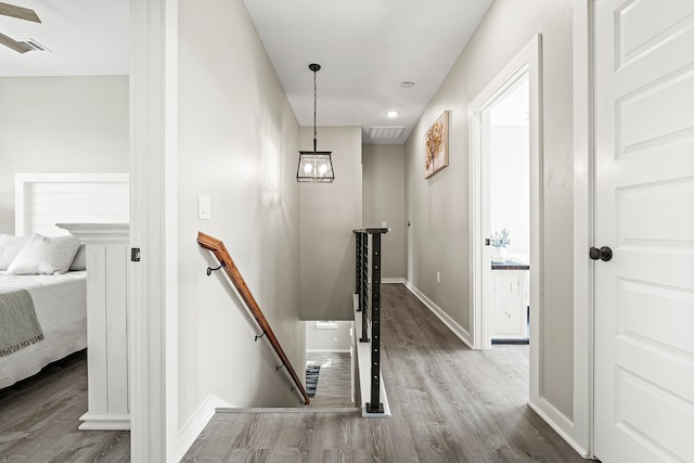 corridor featuring an upstairs landing, visible vents, baseboards, and wood finished floors