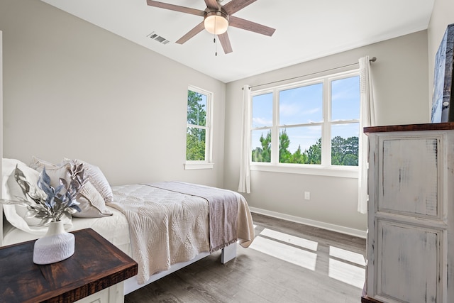 bedroom with visible vents, a ceiling fan, baseboards, and wood finished floors