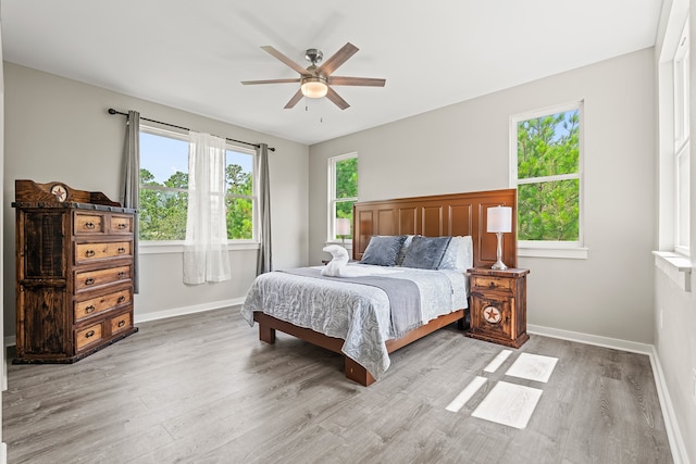 bedroom featuring light wood-style flooring, multiple windows, and baseboards