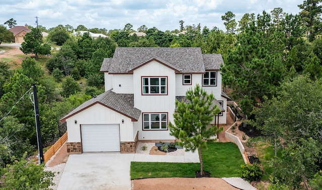 view of front of property with concrete driveway, a garage, stone siding, and roof with shingles