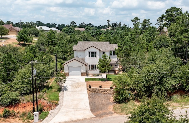 view of front of property with a shingled roof, concrete driveway, a garage, stone siding, and board and batten siding