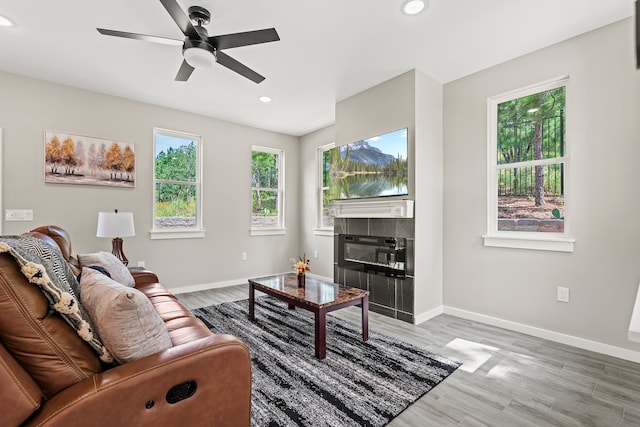 living area with a tiled fireplace, recessed lighting, baseboards, and light wood-type flooring