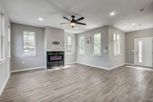 108 Kimo Ct, Bastrop, TX 78602 - unfurnished living room featuring baseboards, ceiling fan, wood finished floors, a tile fireplace, and recessed lighting