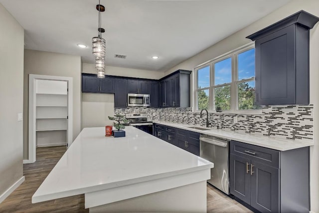 108 Kimo Ct, Bastrop, TX 78602 - kitchen with stainless steel appliances, decorative backsplash, a center island, a sink, and baseboards