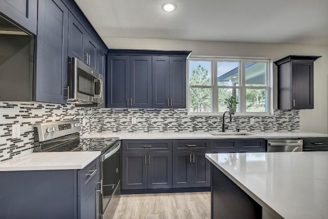108 Kimo Ct, Bastrop, TX 78602 - kitchen featuring appliances with stainless steel finishes, a sink, light countertops, decorative backsplash, and light wood finished floors