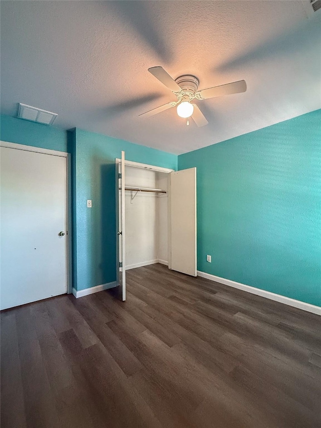 unfurnished bedroom with a textured ceiling, ceiling fan, a closet, and dark hardwood / wood-style floors