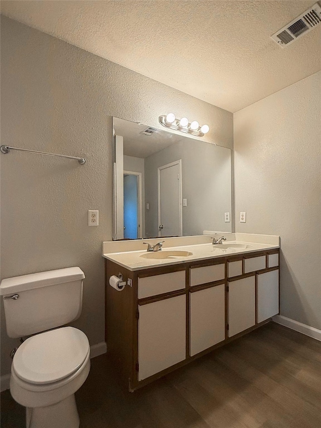 bathroom with hardwood / wood-style floors, toilet, vanity, and a textured ceiling