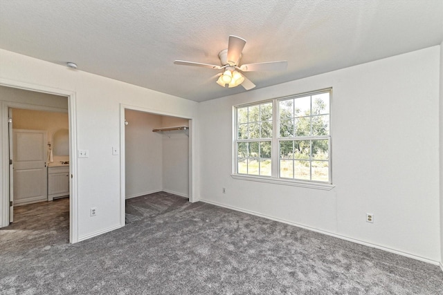 unfurnished bedroom featuring a textured ceiling, ceiling fan, a closet, and dark colored carpet