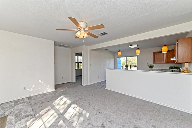 unfurnished living room featuring ceiling fan, light carpet, plenty of natural light, and a textured ceiling