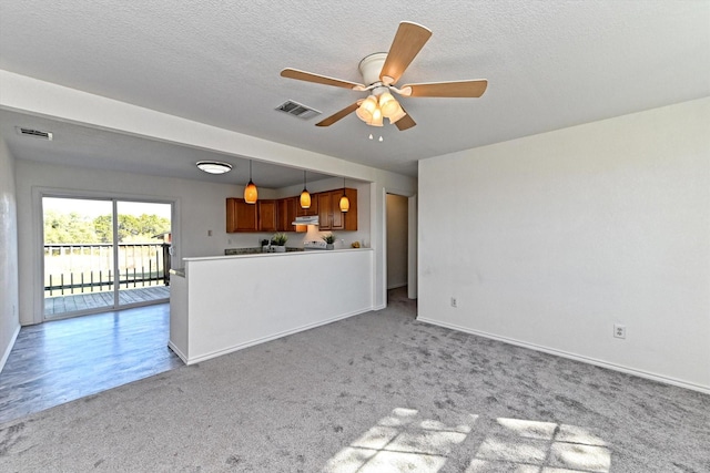 unfurnished living room with ceiling fan, light colored carpet, and a textured ceiling